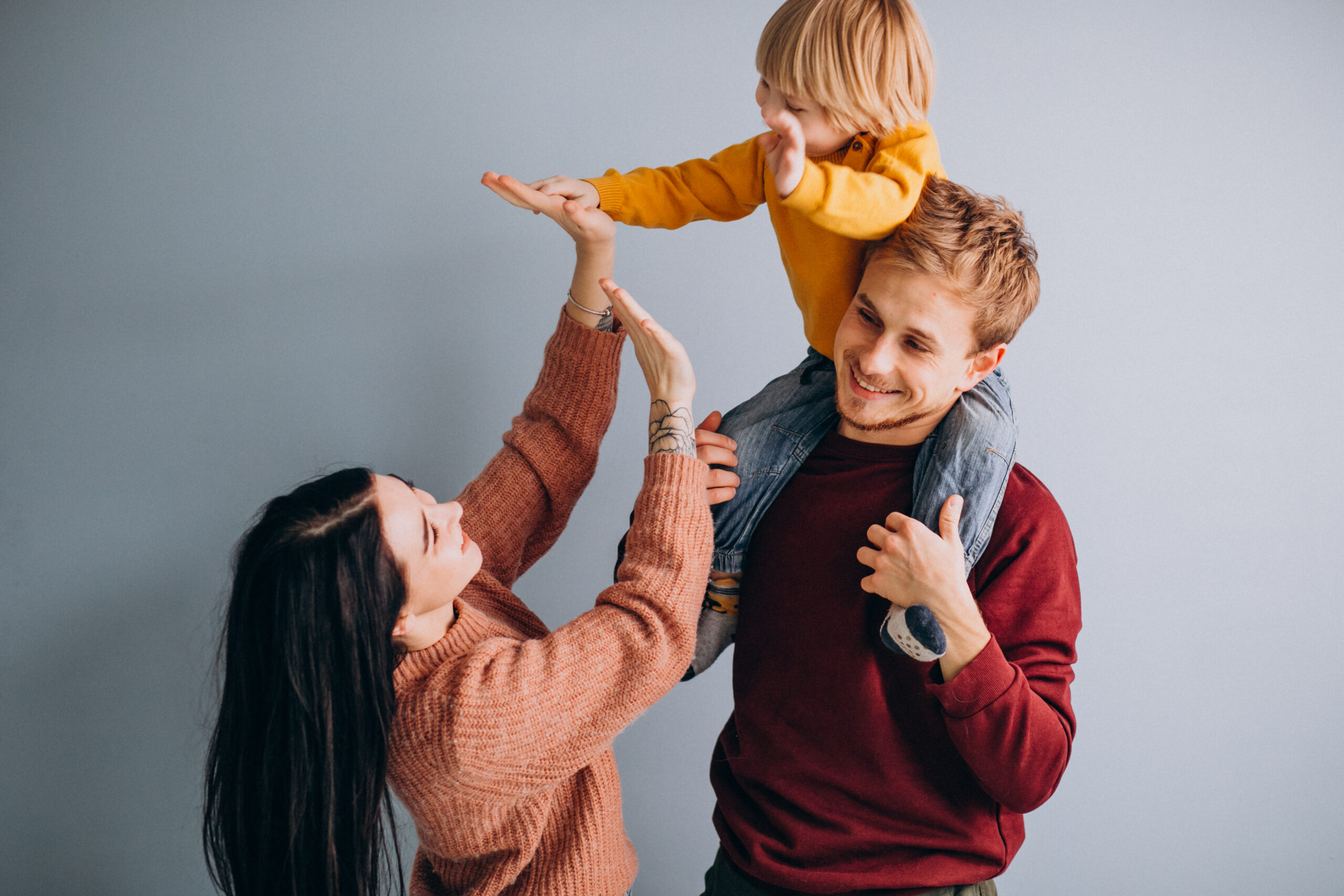 Young family with little son together on grey background